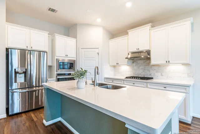 a kitchen with stainless steel appliances a sink a stove a refrigerator and cabinets