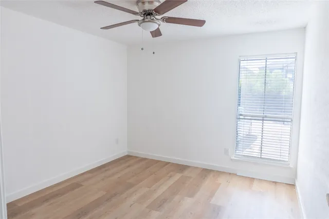 an empty room with a window and a fan