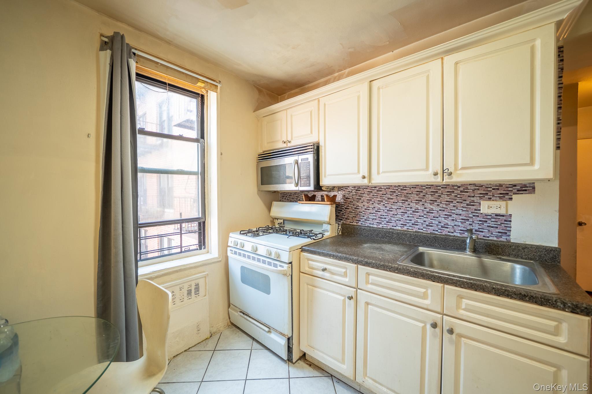 108-49 63rd Avenue, Unit 4A Queens, NY 11375 - Photo 6 of 10 a kitchen with white cabinets and white appliances