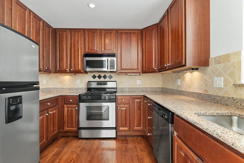 36 Village Road, Unit 715 Middleton, MA 01949 - Photo 2 of 32 a kitchen with granite countertop wooden cabinets a stove and a sink