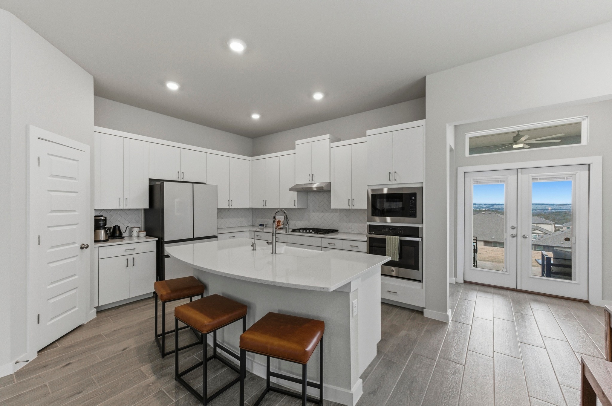 1209 Bluewood Bend Leander, TX 78641 - Photo 8 of 40 a large kitchen with kitchen island a stove a refrigerator a sink a dining table and chairs with wooden floor