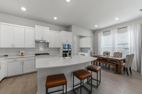 a kitchen with stainless steel appliances a table and chairs in it