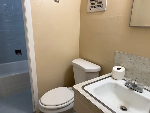 a white toilet sitting next to a bath tub