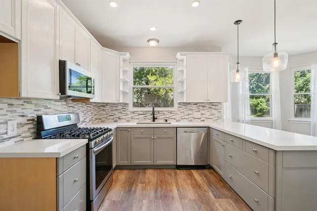 a view of an empty room with wooden floor fireplace and a window
