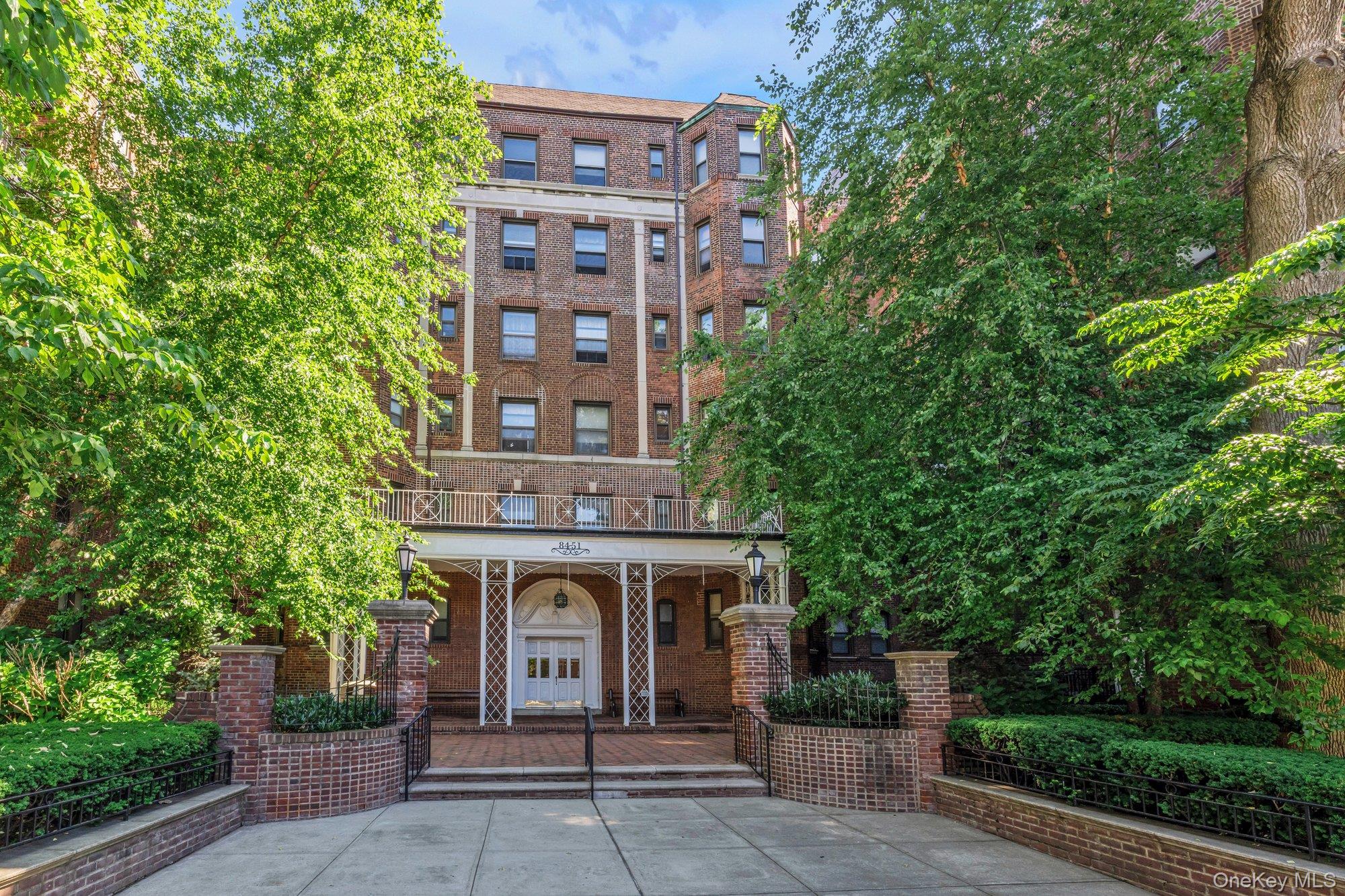 84-51 Beverly Road, Unit 6A Queens, NY 11415 - Photo 1 of 14 front view of a brick house with a small yard