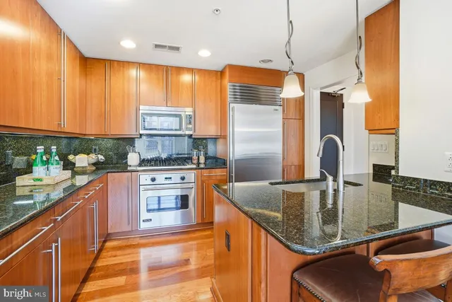 a kitchen with granite countertop a sink stainless steel appliances and cabinets