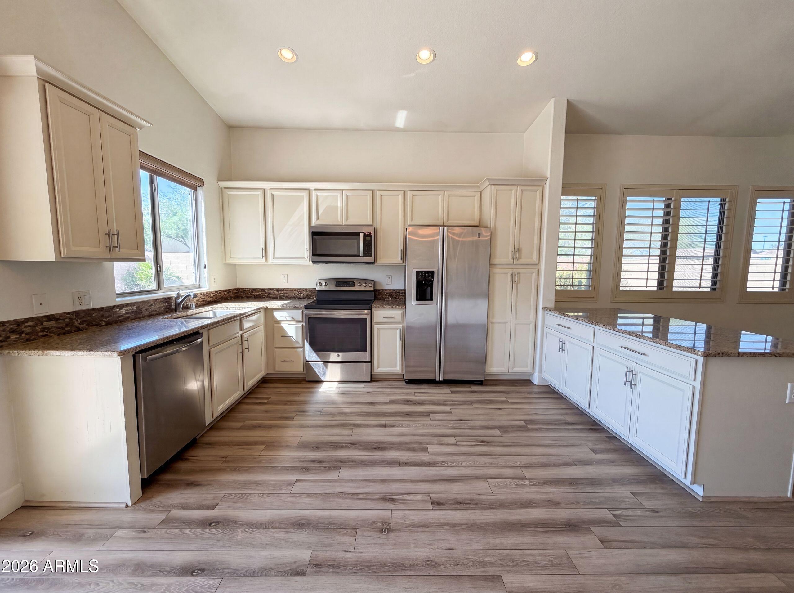 3951 East Timberline Road Gilbert, AZ 85297 - Photo 6 of 28 a large kitchen with cabinets wooden floor and stainless steel appliances
