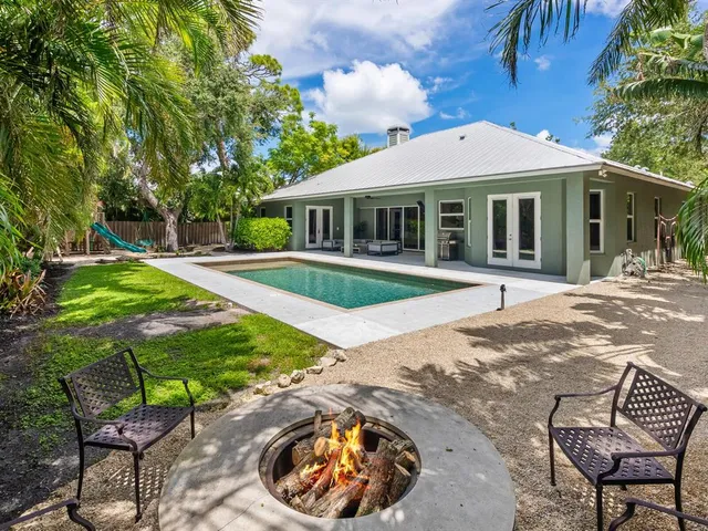 a kitchen with stainless steel appliances granite countertop a stove top oven a sink dishwasher a dining table and chairs with wooden floor