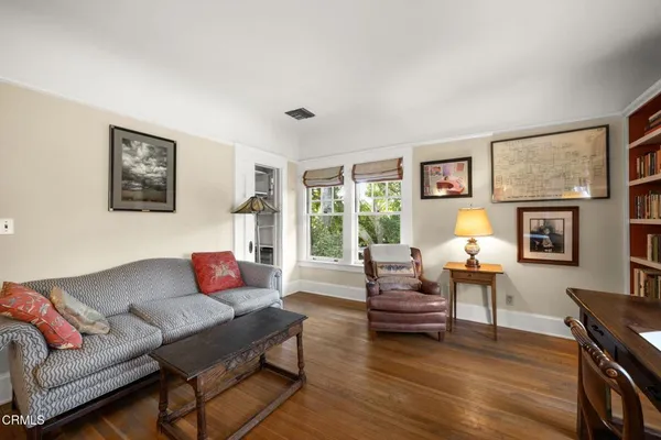 a living room with furniture a chandelier and a dining table with wooden floor