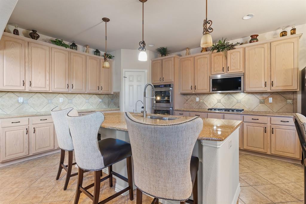 2228 Condor Street Grand Prairie, TX 75052 - Photo 14 of 33 a kitchen with kitchen island granite countertop a table chairs microwave and cabinets
