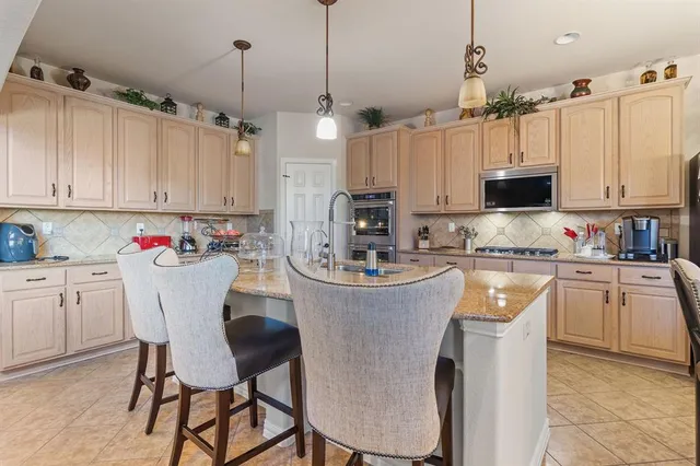 a view of kitchen with stainless steel appliances kitchen island granite countertop dining table chairs and a view of living room