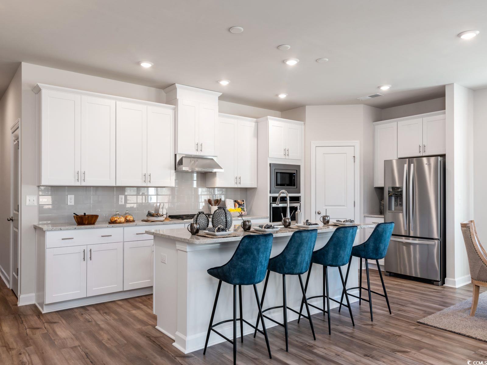 112 Red Cedar Court Longs, SC 29568 - Photo 2 of 13 Kitchen featuring a kitchen bar, stainless steel appliances, decorative backsplash, dark wood-style flooring, and recessed lighting