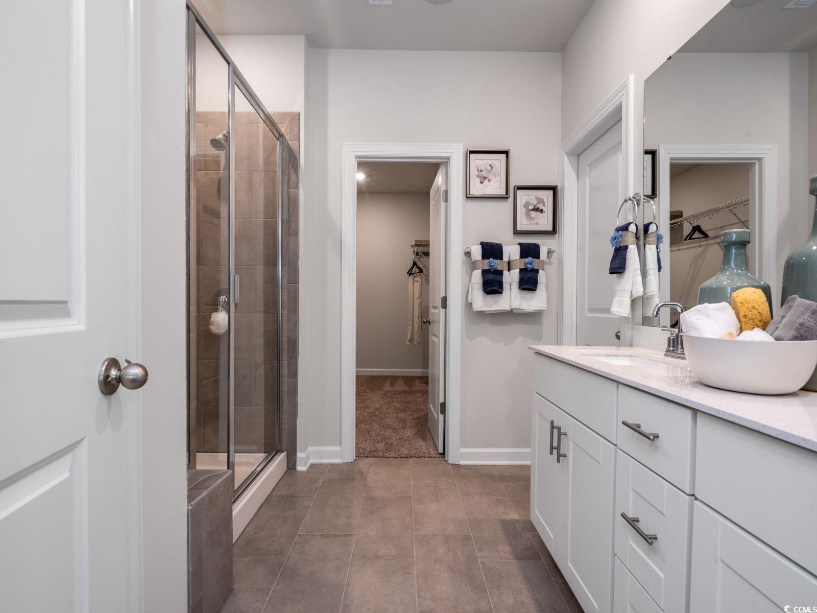 112 Red Cedar Court Longs, SC 29568 - Photo 7 of 13 Bathroom with a walk in closet, a shower stall, double vanity, and dark tile patterned flooring