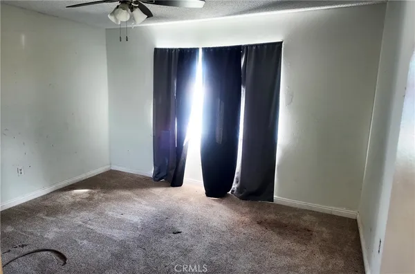 an empty room with a ceiling fan and window