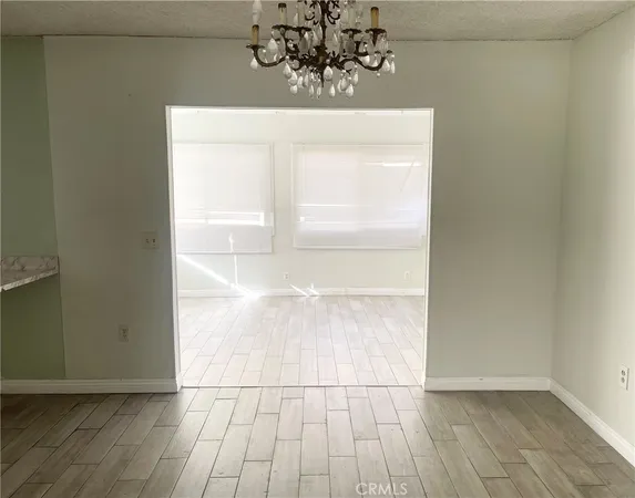 an empty room with wooden floor and chandelier