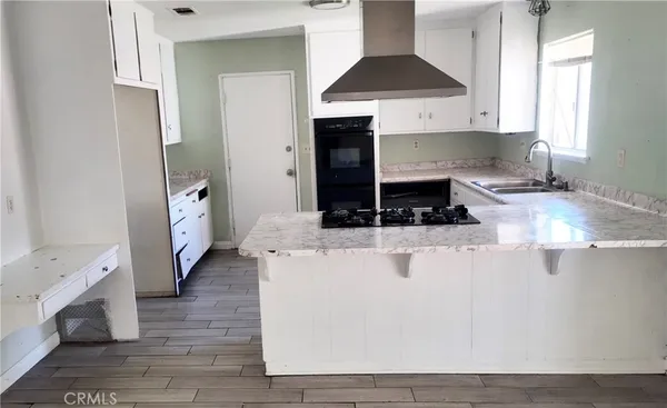 a kitchen with granite countertop a stove a sink and a refrigerator