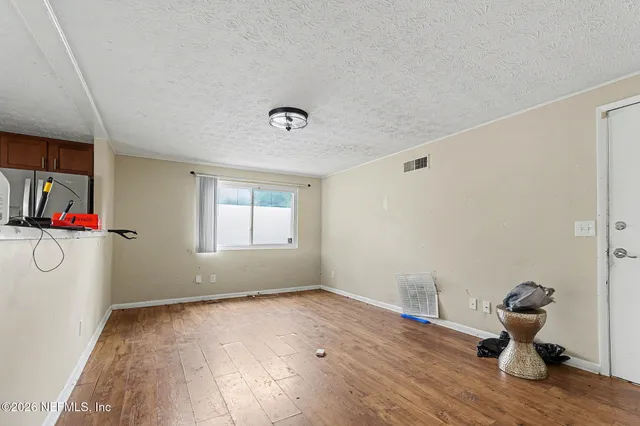 a view of empty room with wooden floor and fan