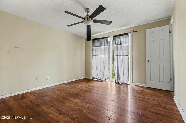 an empty room with wooden floor and windows