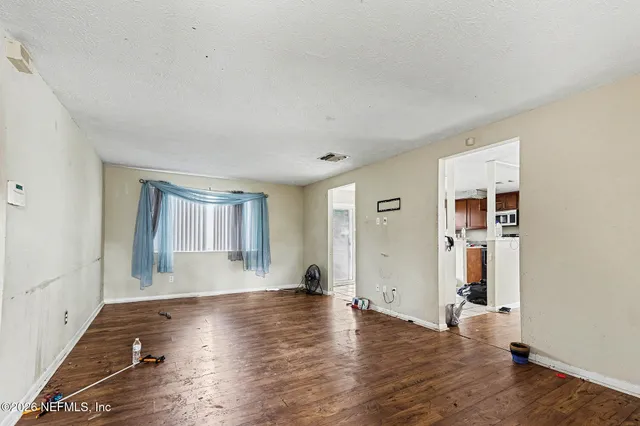 an empty room with wooden floor and windows