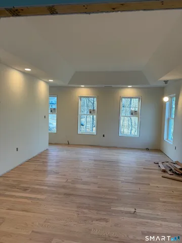a view of an empty room with window and wooden floor
