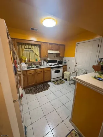 a kitchen with granite countertop a sink a stove top oven and cabinetry