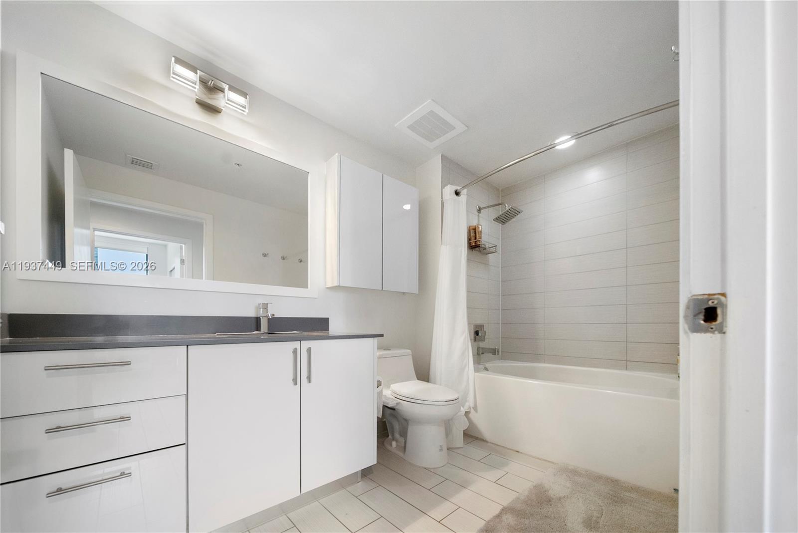 999 Southwest 1st Avenue, Unit 1617 Miami, FL 33130 - Photo 9 of 12 a bathroom with a granite countertop sink mirror toilet and bathtub