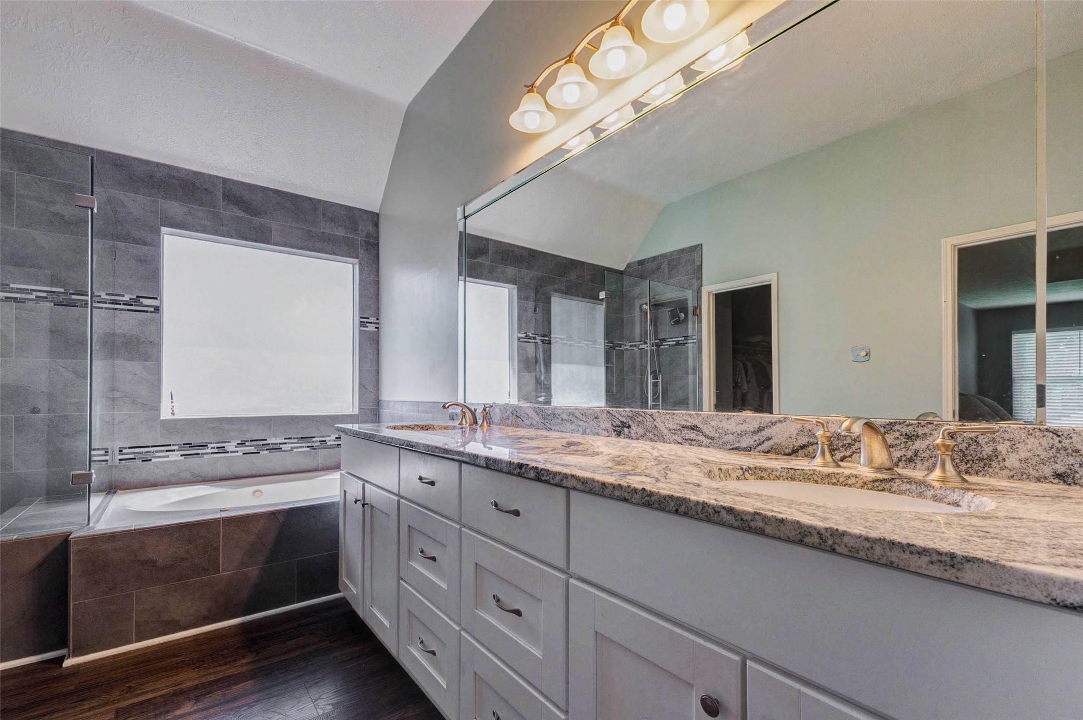 9215 Landry Boulevard Spring, TX 77379 - Photo 29 of 42 The relaxing soaking tub is positioned beneath an obscure window that welcomes natural light while maintaining privacy. Elegant tile surrounds and a decorative accent tile detail add a luxurious designer touch to the space.
