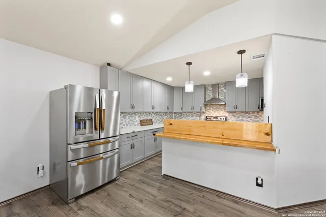 a large kitchen with stainless steel appliances kitchen island granite countertop a refrigerator and a stove top oven