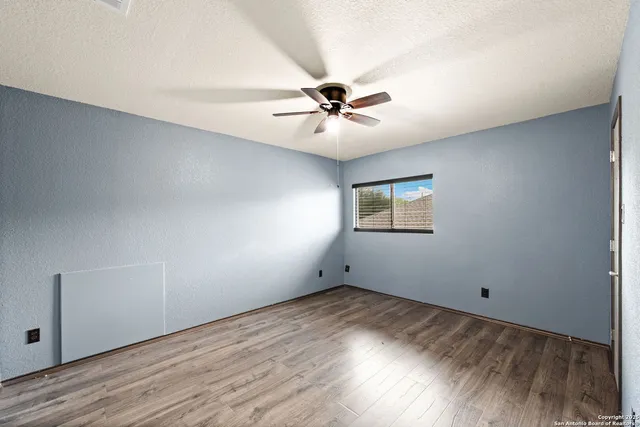 an empty room with wooden floor and ceiling fan