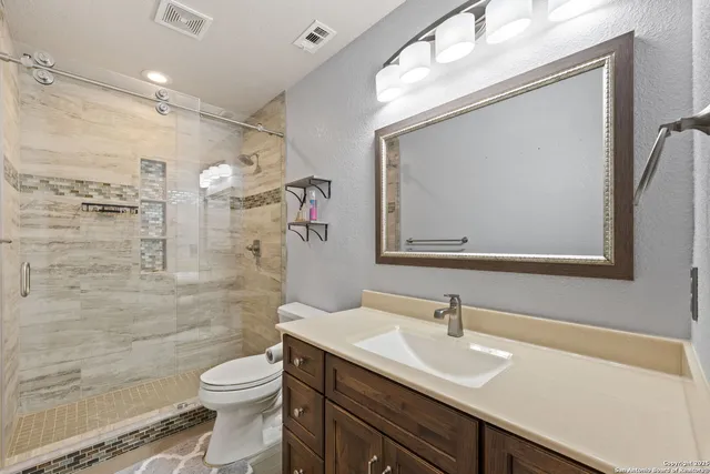 a bathroom with a sink a toilet a mirror and shower