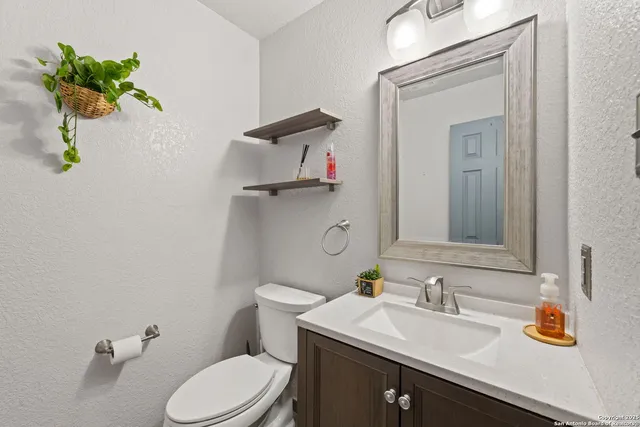 a bathroom with a granite countertop toilet sink and mirror