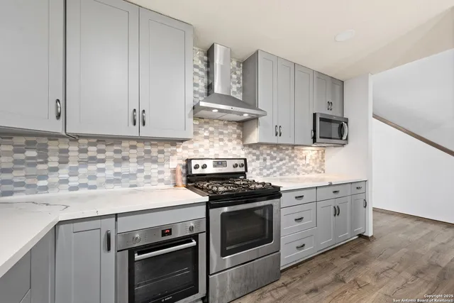 a kitchen with stainless steel appliances granite countertop white cabinets and stove