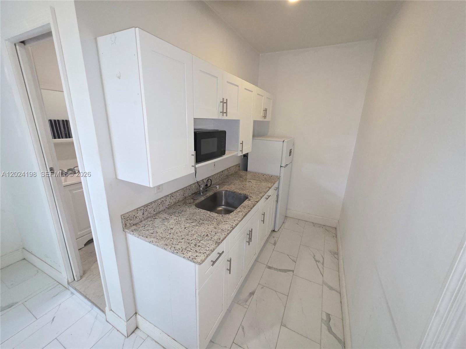 651 East 48th Street Hialeah, FL 33013 - Photo 38 of 52 a kitchen with a sink a stove and a microwave