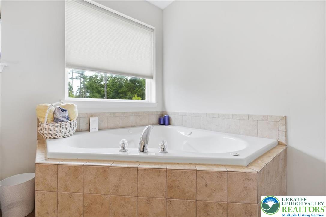 5032 Custard Road Stroudsburg, PA 18360 - Photo 38 of 80 A tiled corner soaking tub sits beneath a large window framing serene wooded views.