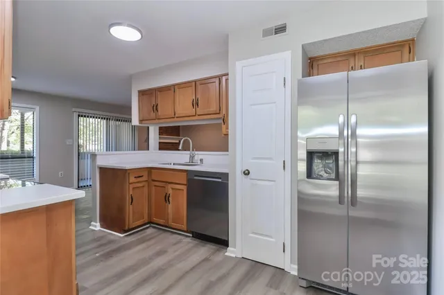 a kitchen with kitchen island granite countertop a refrigerator a sink a stove and white cabinets with wooden floor