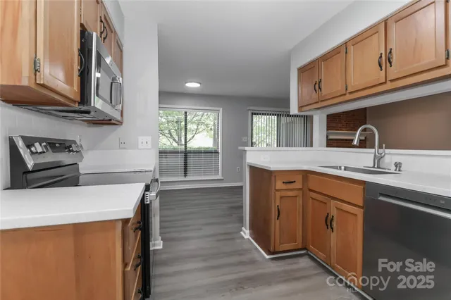 a kitchen with stainless steel appliances granite countertop a sink a stove cabinets and wooden floor