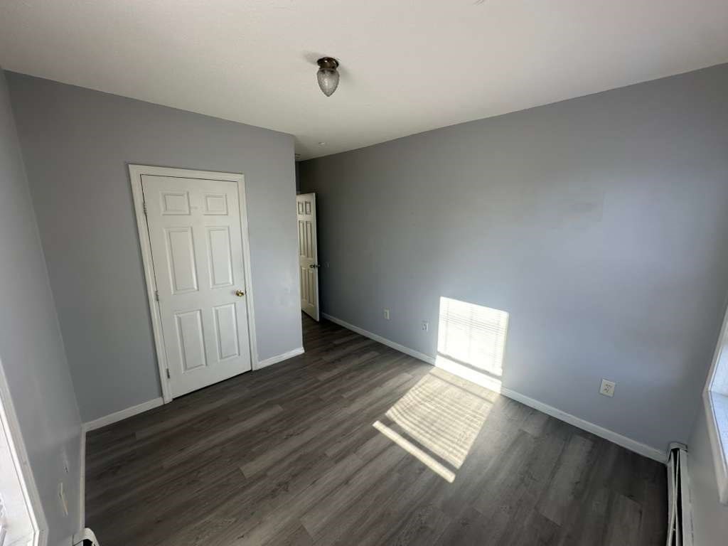 27 Willow Street, Unit A Lawrence, MA 01841 - Photo 8 of 29 an empty room with wooden floor and windows