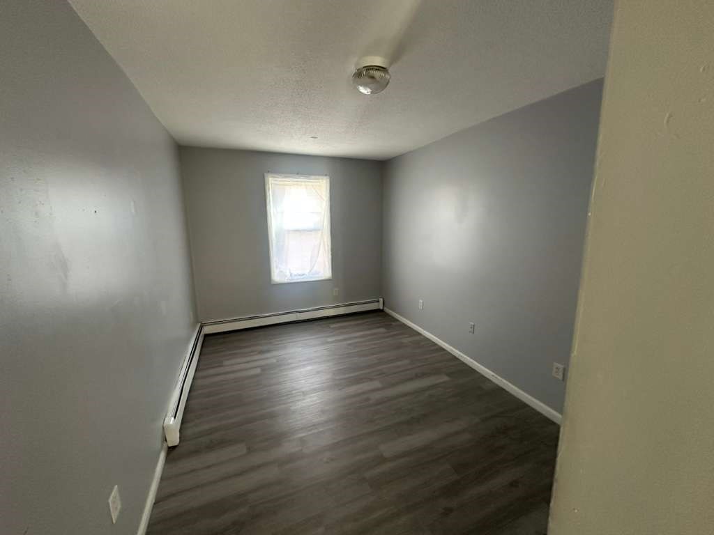 27 Willow Street, Unit A Lawrence, MA 01841 - Photo 10 of 29 an empty room with wooden floor and windows