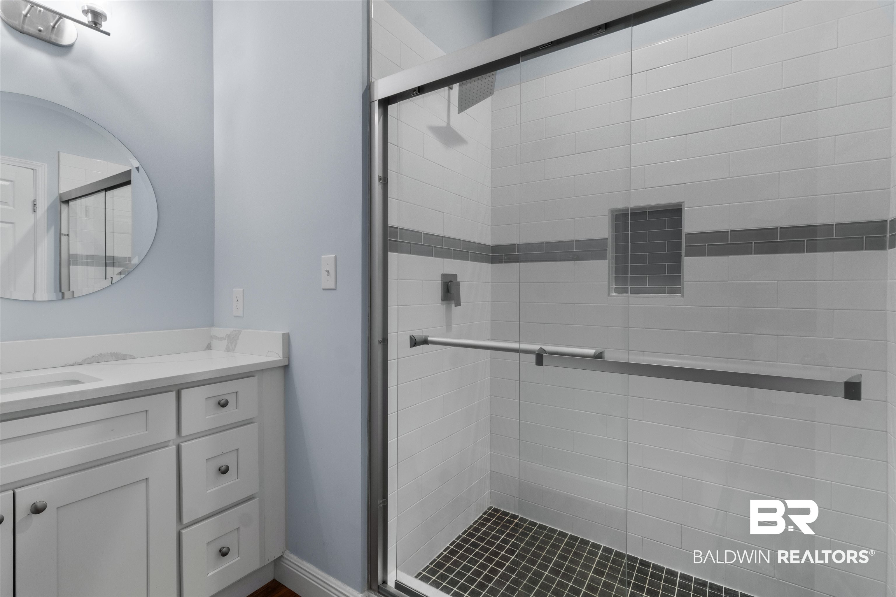 927 Periwinkle Lane Foley, AL 36535 - Photo 13 of 26 Glass-enclosed shower featuring white subway-style tile, a gray accent band, an integrated shower niche, and a dark tile floor