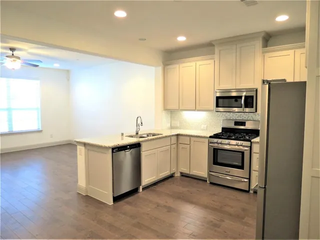 a kitchen with stainless steel appliances granite countertop a stove a sink and a refrigerator