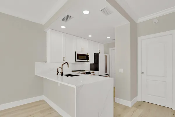 a kitchen with stainless steel appliances a sink a microwave a refrigerator and a counter top space