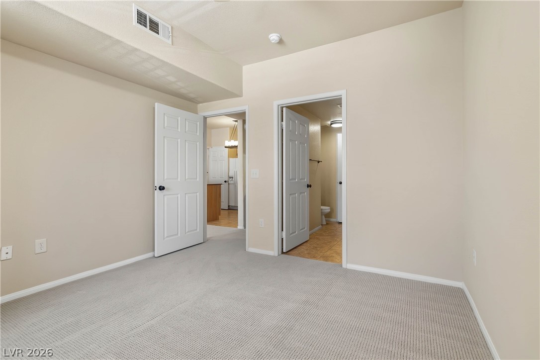 10550 West Alexander Road, Unit 2060 Las Vegas, NV 89129 - Photo 26 of 45 Well-lit room with plush carpet, offering access to a kitchen and a bathroom.