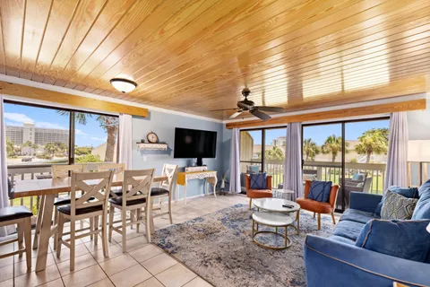 a living room with furniture a flat screen tv and floor to ceiling windows