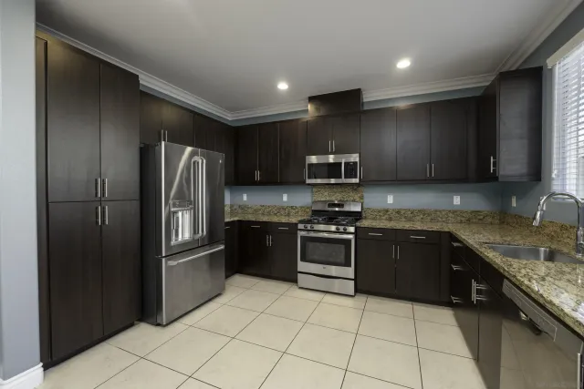 a large kitchen with stainless steel appliances granite countertop a refrigerator and a stove top oven