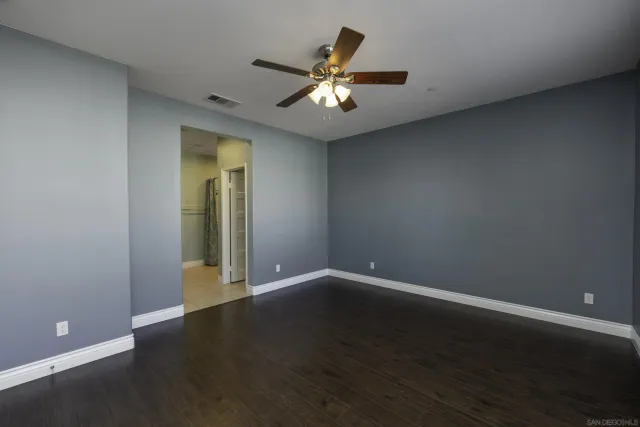 an empty room with wooden floor and fan