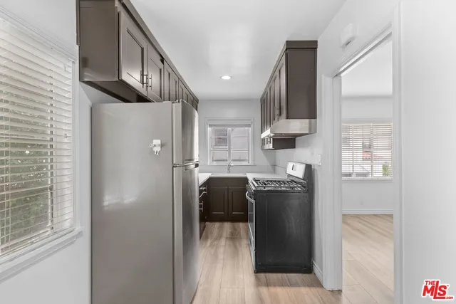 a kitchen with stainless steel appliances granite countertop a refrigerator a sink a stove and a refrigerator with wooden floor