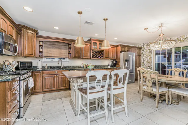 a kitchen with stainless steel appliances kitchen island granite countertop a table chairs and a refrigerator