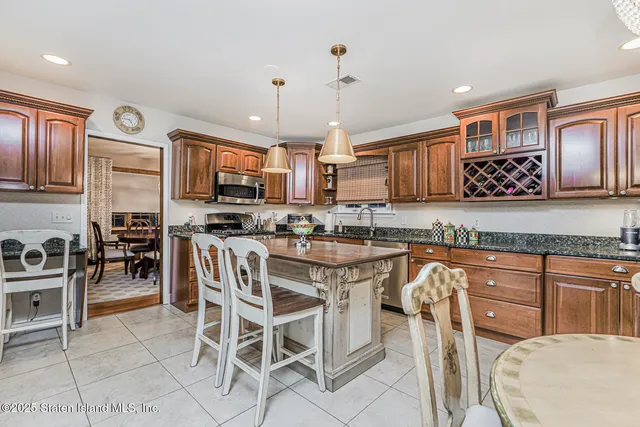 a kitchen with stainless steel appliances granite countertop a stove top oven a sink a dining table and chairs with wooden floor