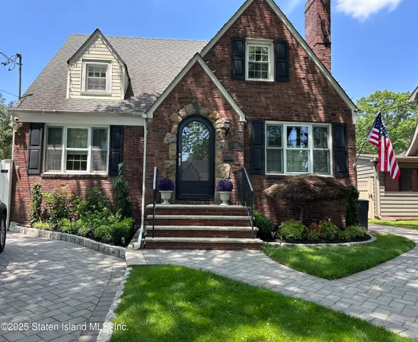 a front view of a house with a yard and potted plants