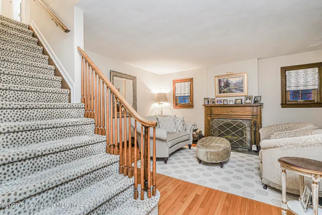 a view of a livingroom with furniture a fireplace wooden floor and windows